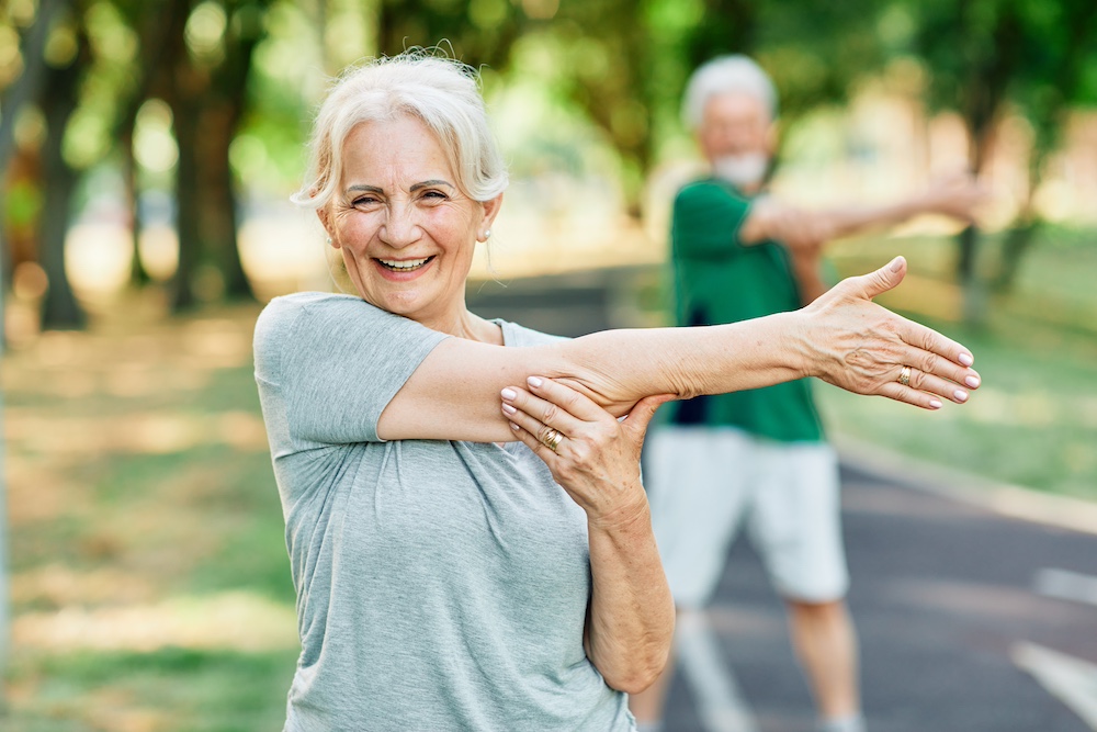 A senior woman stretching and exercising at an outdoor fitness class